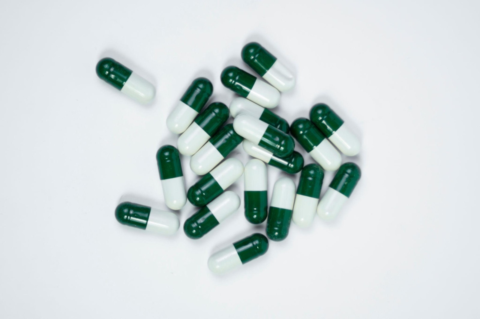 Green and white pharmaceutical capsules representing oral medication